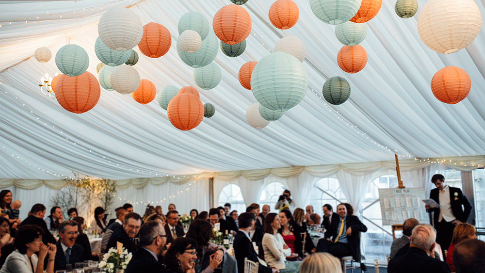 Complementary coloured paper lanterns warm up a white wedding marquee